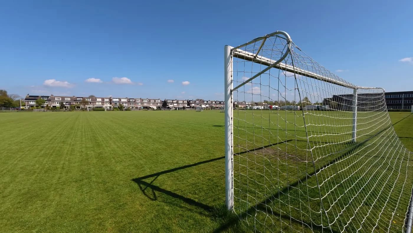 An empty grass sports field with a soccer goal and no players on it